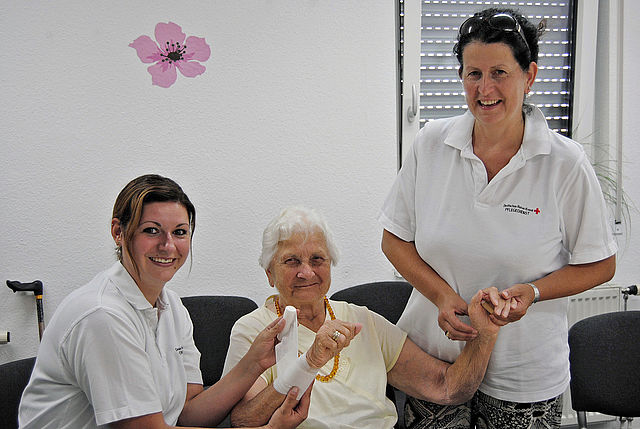 Zwei Pflegekräfte messen bei Seniorin den Blutzucker