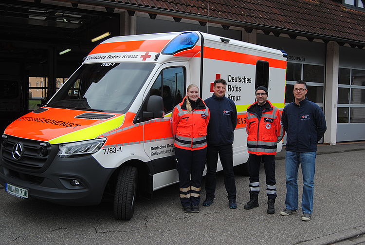 Vier Personen, zwei davon in PSA, stehen vor dem neuen Rettungswagen