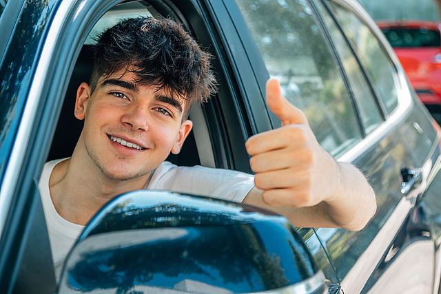 Ein junger Mann freut sich, dass er Auto fährt.